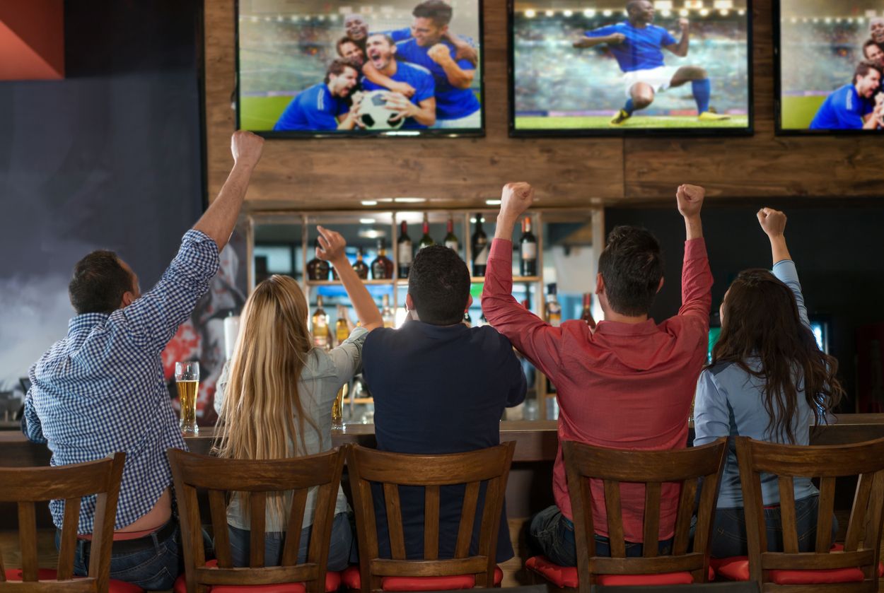 Fans enjoying game night at a sports bar near Nashville Airport with food and drinks on the table.